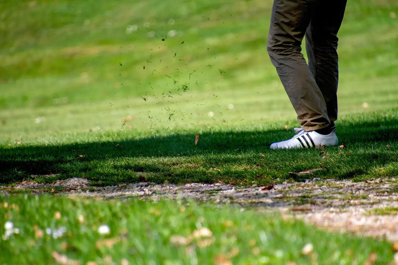 Golfspiller der slår et slag og laver en græsdivot