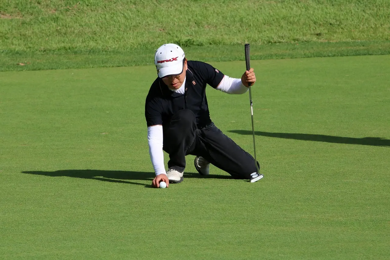Golfspiller på green der placerer en golfbold og holder en putter